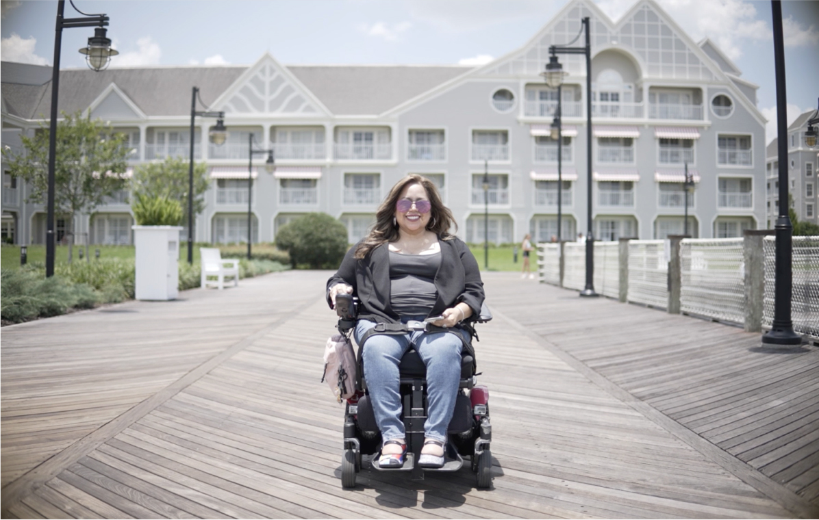 Keishla, adult with SMA, sitting in a power chair.